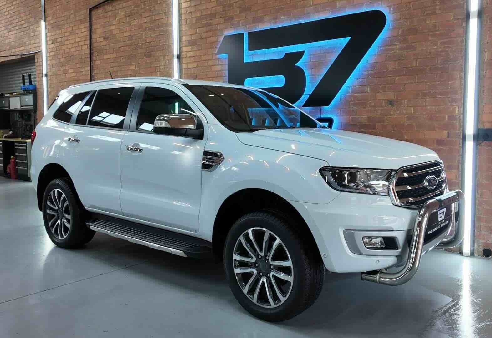 White Ford Everest SUV in garage with neon 137 logo on brick wall before enhancement