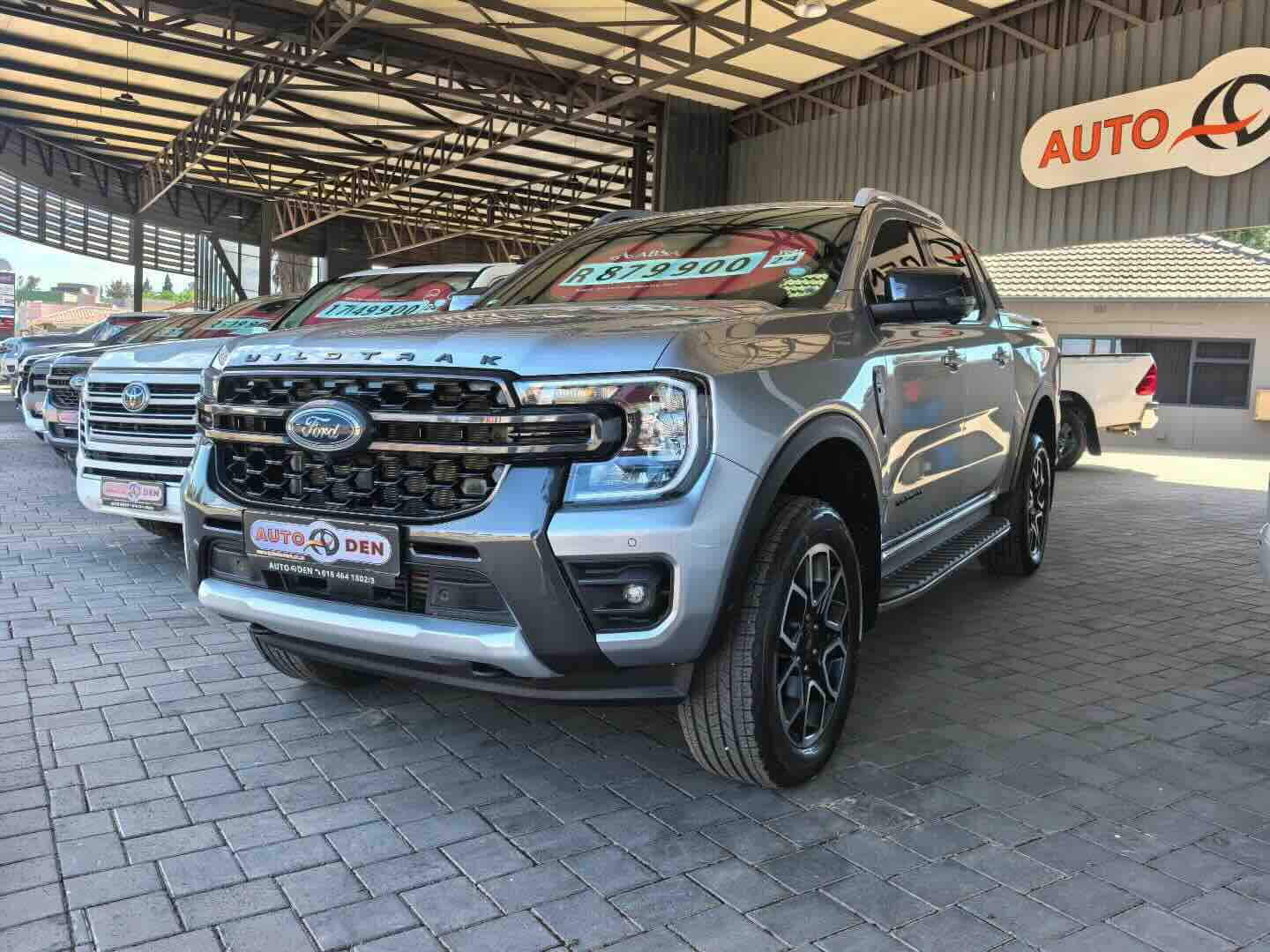 Ford truck at dealership lot with price stickers and signage before background cleanup